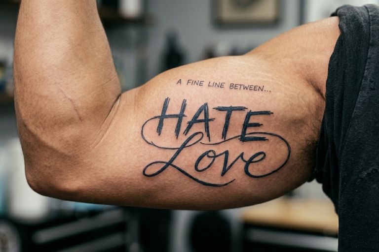 A man having love hate ambigram tattoo on his arm muscle.